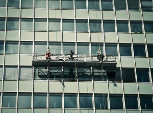 Commercial window cleaners in a cradle on a high-rise building.