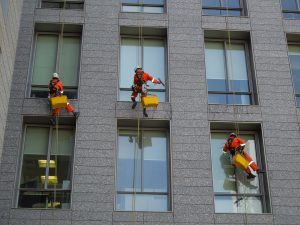 Commercial window cleaners cleaning high-rise building using rope access equipment.