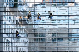 Commercial window cleaners cleaning high-rise building using rope access.